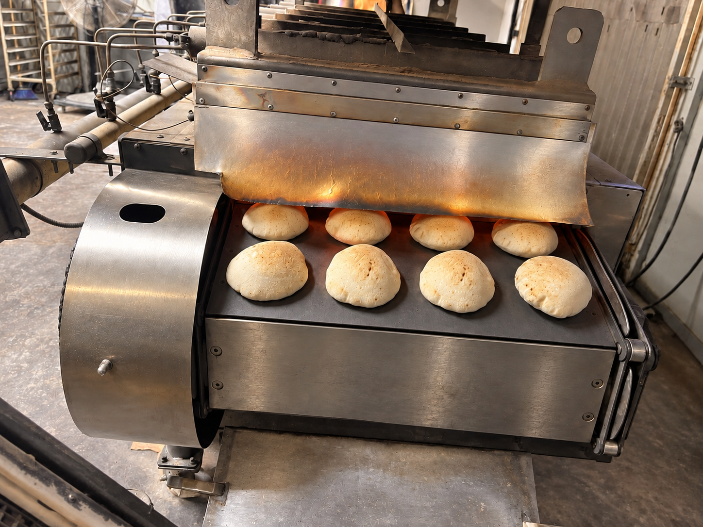 Fresh pitas emerging in rows from the Pita House bakery oven